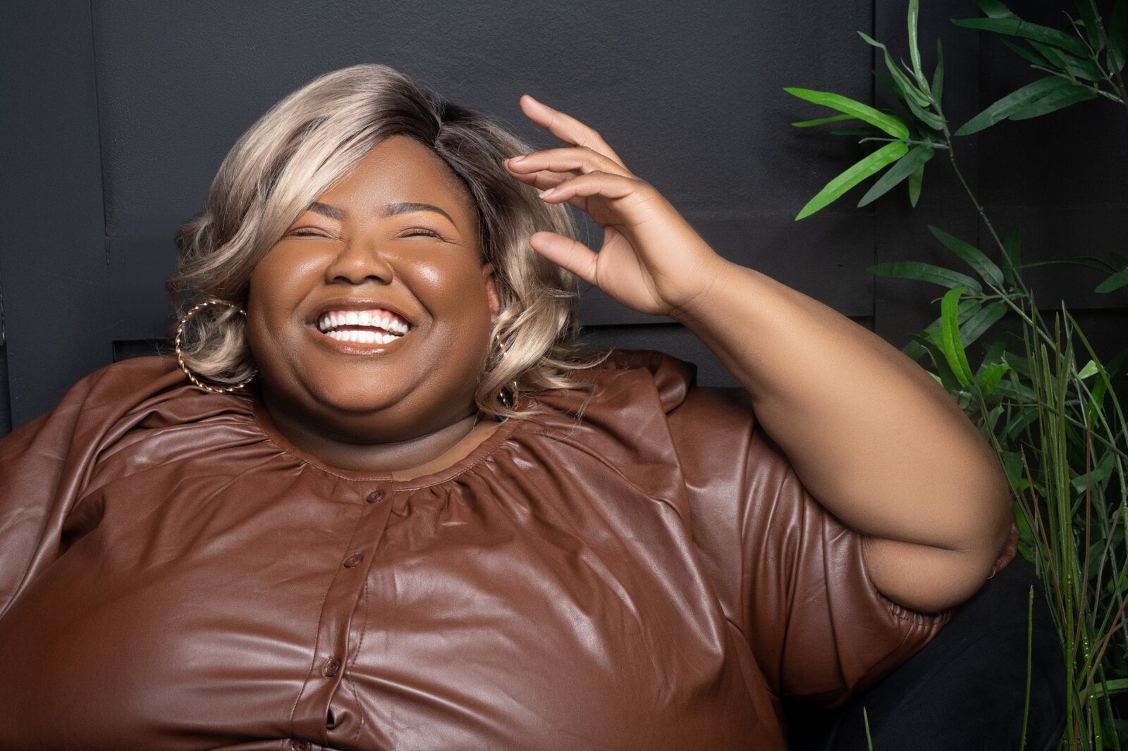 Cori laughing during a portrait session in a rich brown outfit